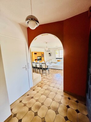 A hallway with a tiled floor leading to a dining area with chairs and a table. - Villa' Tyno Excellence familiale - 18 couchages (La Teste-de-Buch)