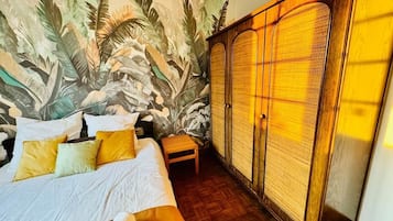 A bedroom with a bed, a nightstand, a wardrobe, and a mural on the wall.