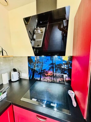 A kitchen with a black induction cooktop, a kettle, and a toaster on the counter. - Villa' Tyno Excellence familiale - 18 couchages (La Teste-de-Buch)