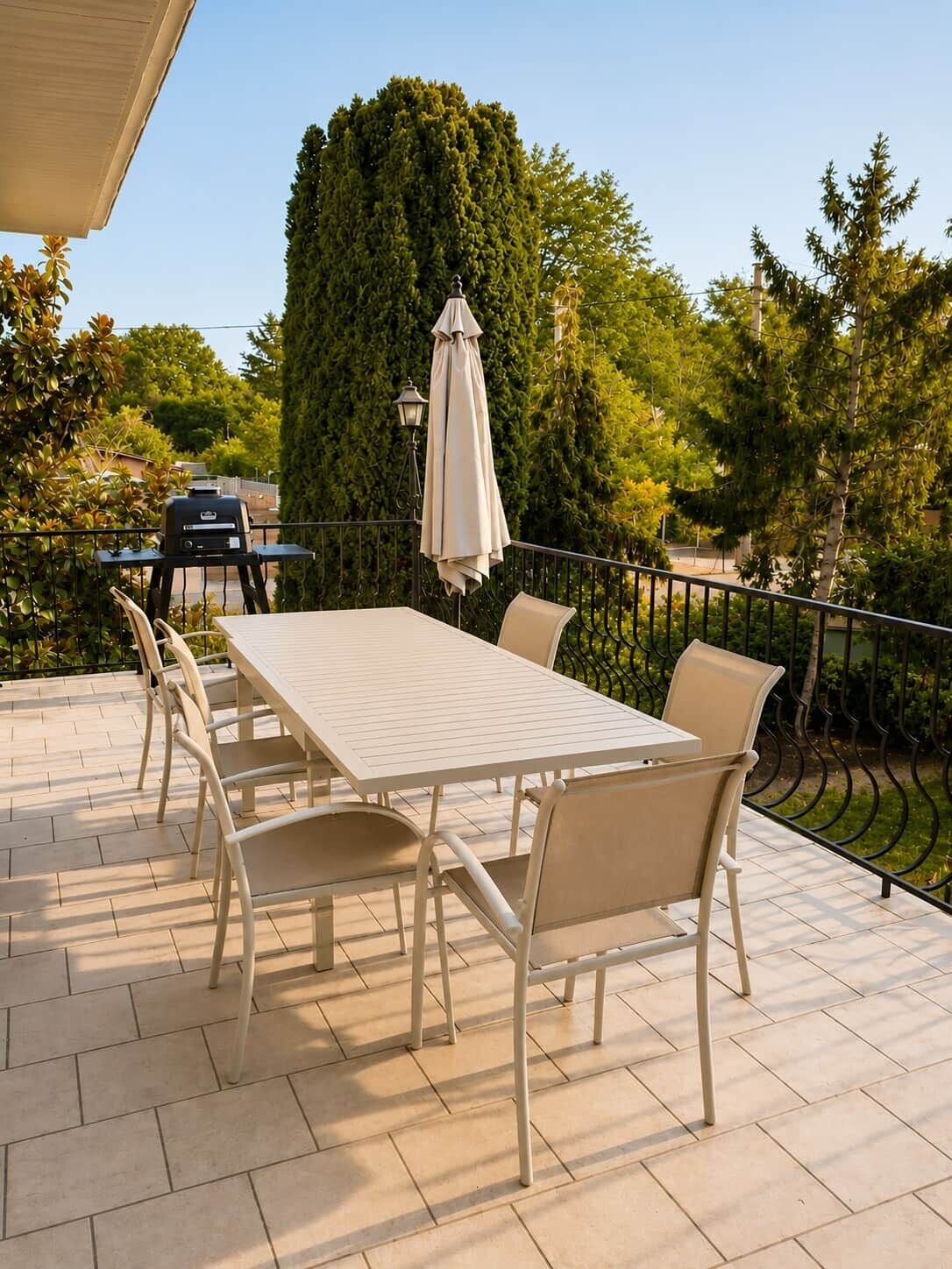An outdoor patio with a table and chairs, a grill, and a lamp.