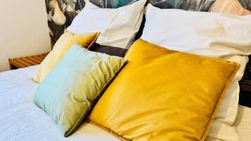 Ein Bett mit zwei Kissen, eines hellgrün und eines gelb, und einem Kopfstück mit einem Blumenmuster.