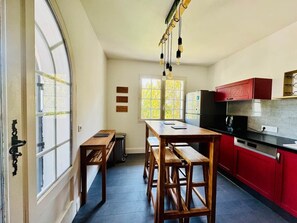 A kitchen with wooden benches, a red cabinet, and a window with a view. - Villa' Tyno Excellence familiale - 18 couchages (La Teste-de-Buch)