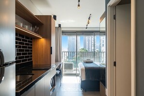 A modern apartment with a kitchen, a balcony with a bed, and a view of high-rise buildings. - Comfort in Condo. w/ Pool & City View SP Lss0620 (São Paulo)