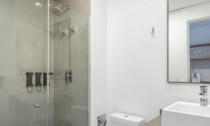 A modern bathroom with a glass-enclosed shower, a white sink, and a mirror reflecting a bathroom vanity. - Comfort in Condo. w/ Pool & Balcony Lss1319 (São Paulo)