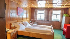 Una habitación de madera con una cama, una silla y una ventana.