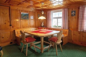 A wooden interior with a dining table, chairs, and a hanging light fixture. - The Bonawinkelhus (Gaschurn)