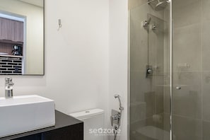 A modern bathroom with a white sink, a toilet, and a glass-enclosed shower area. - Comfort With Balcony and Pool Lss1010 (São Paulo)