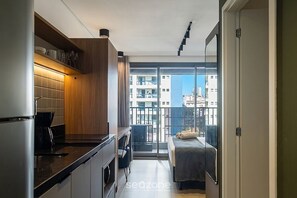 A compact kitchen with modern appliances, a dining area, and a balcony with a city view. - Comfort With Pool in Sao Paulo Lss0513 (São Paulo)