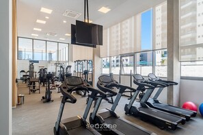 A gym with treadmills, exercise bikes, and weight machines. - Comfort in Condo w/ Pool and City View Lss1317 (São Paulo)