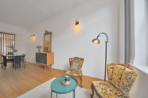 Una sala de estar con comedor, un sofá, una silla, una lámpara y un espejo.