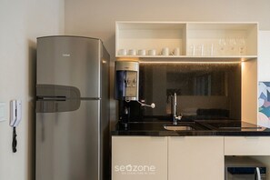Eine moderne Küche mit einem Edelstahlkühlschrank, einer Kaffeemaschine und einer Mikrowelle.