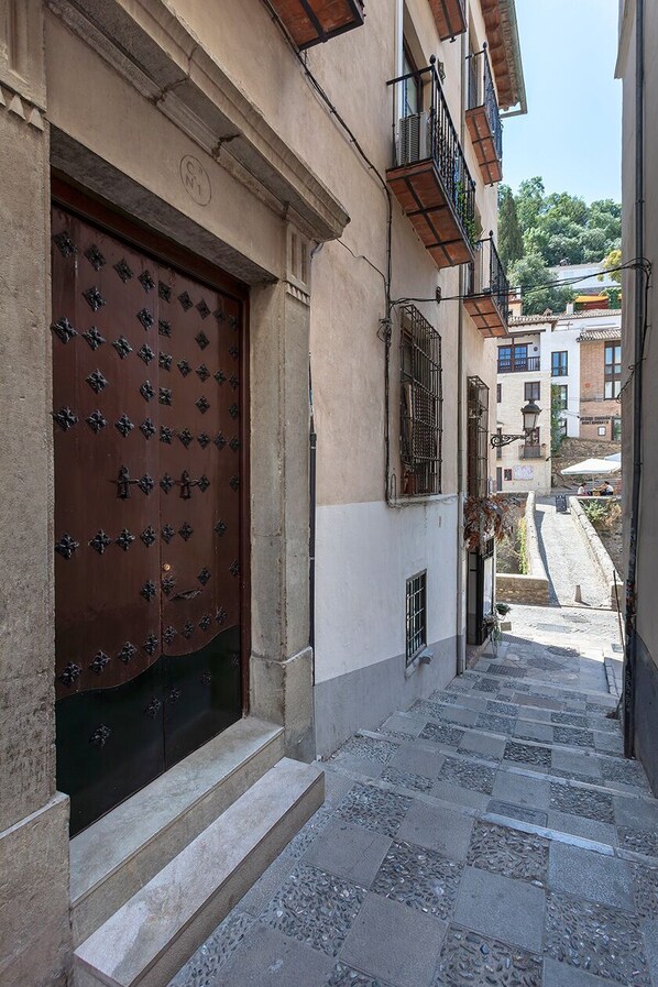 A narrow street with a large ornate door and steps leading up to a building. - Genteel Home Santa Ines (Granada)