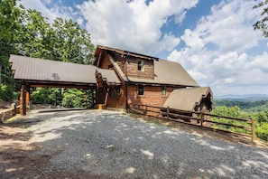 A rustic cabin with a metal roof, a wooden deck, and a gravel driveway. - Epic Mtn Views • Hot Tub • Fire Pit • Sleeps 13 (Blue Ridge)