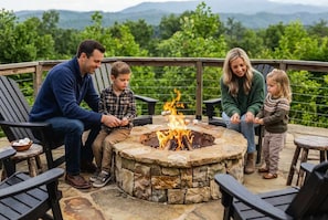 A family around a stone fire pit with a scenic view. - Epic Mtn Views • Hot Tub • Fire Pit • Sleeps 13 (Blue Ridge)