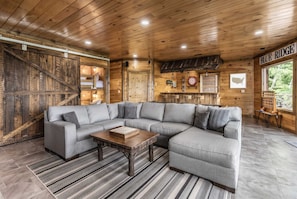 A cozy living room with a sectional sofa, a wooden coffee table, and a herringbone-patterned rug. - Epic Mtn Views • Hot Tub • Fire Pit • Sleeps 13 (Blue Ridge)