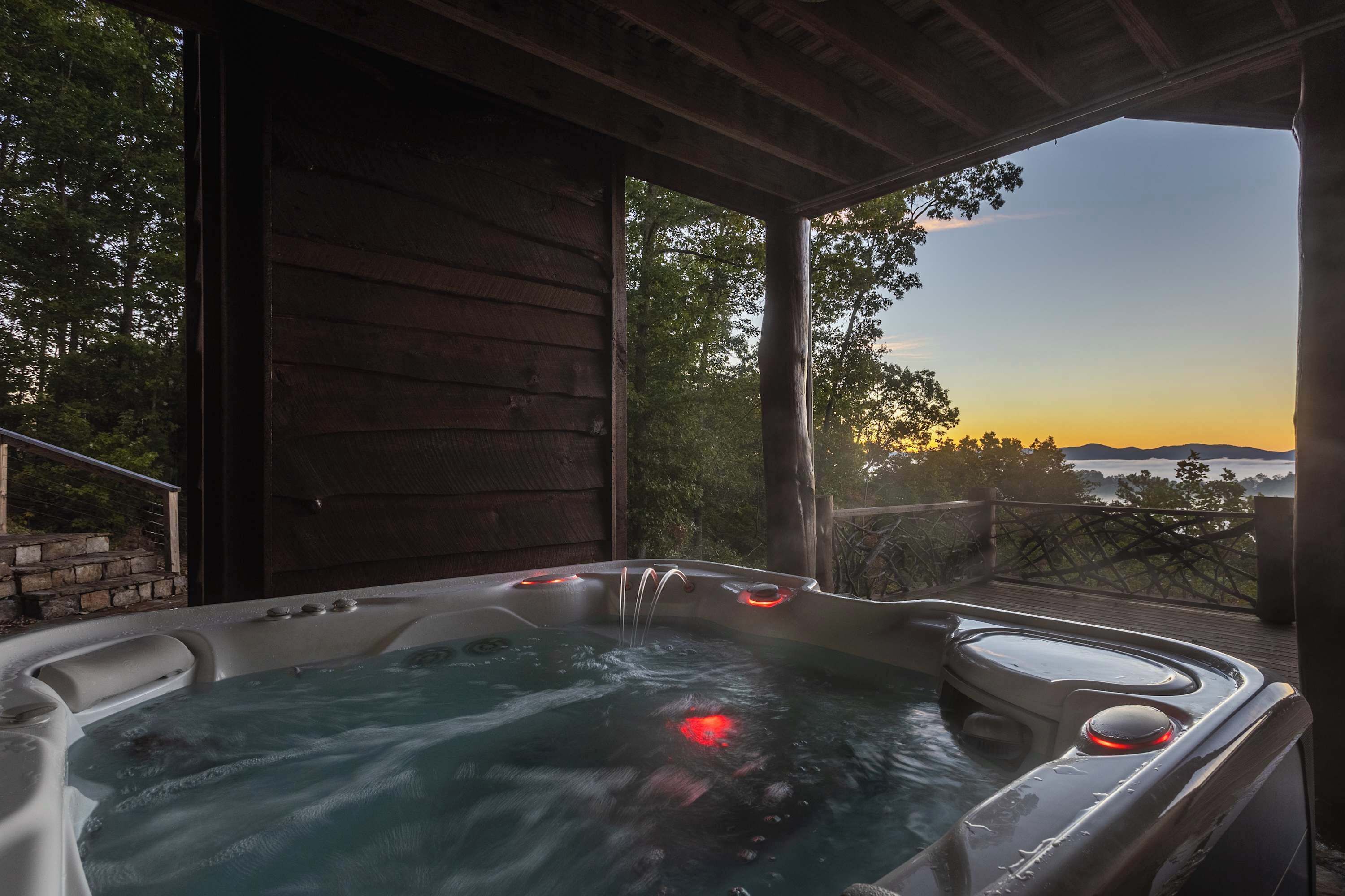 A hot tub with a view of the sunset and a wooden deck.
