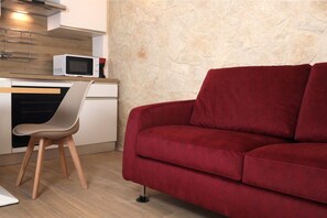A kitchenette with a microwave, a chair, and a red sofa. - Hostmate - Bari - Garruba  (Bari)