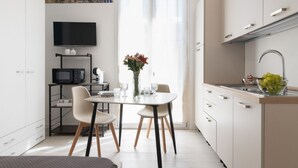 Una cocina compacta con comedor, un televisor sobre la encimera y vista al mar por la ventana.