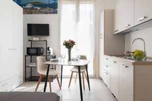 Eine kleine Küche mit Essbereich, einem an der Wand montierten Fernseher und Meerblick durch das Fenster.