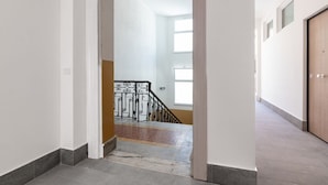 Un pasillo que conduce a una escalera con barandilla metálica.