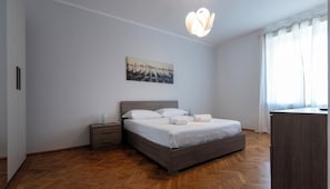 Quarto com uma cama, mesa de cabeceira e um quadro na parede.