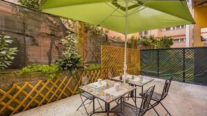 An outdoor patio with a table and chairs, a green umbrella, and a decorative fence. - [LaViaDelleSpezie] next station+ 5Terre + A/C (La Spezia)