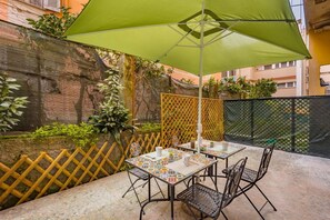 An outdoor patio with a table and chairs, a green umbrella, and a decorative fence. - [LaViaDelleSpezie] next station+ 5Terre + A/C (La Spezia)