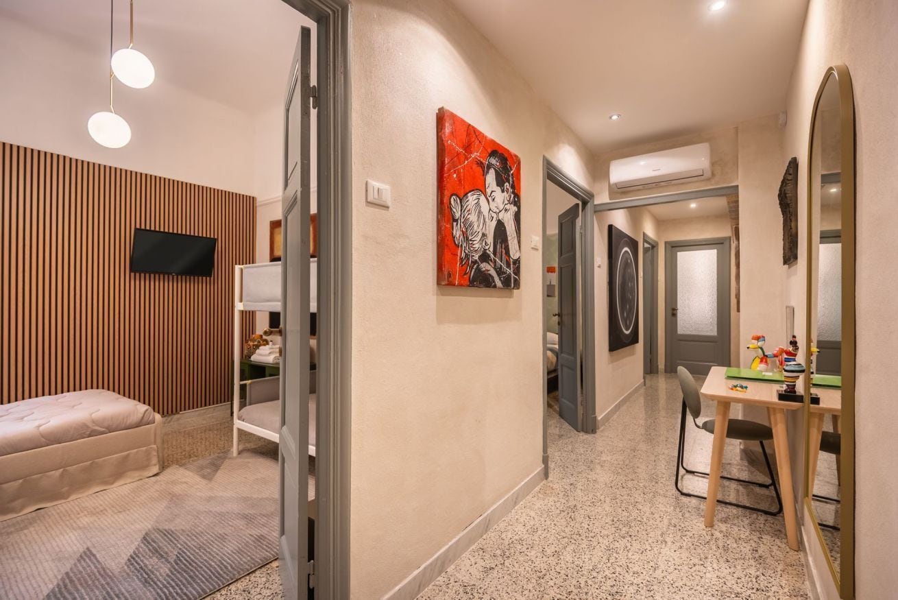 A hotel room with a bed, a desk, a chair, a television, and artwork on the walls.