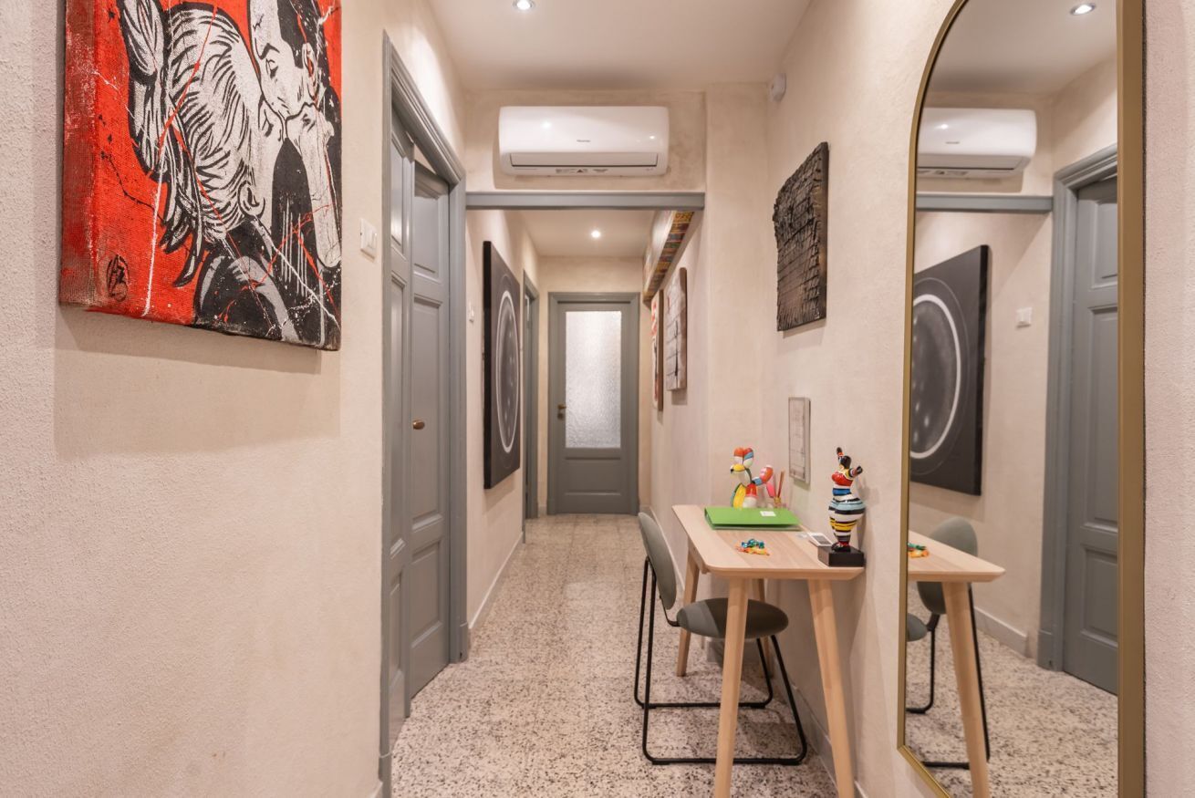 Un couloir comprenant une table à manger, des chaises et des œuvres d’art accrochées aux murs.