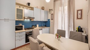 A modern kitchen with a dining area, featuring a white table, chairs, and a decorative toy on the table. - [LaViaDelleSpezie] next station+ 5Terre + A/C (La Spezia)