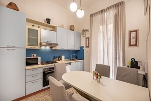 A modern kitchen with a dining area, featuring a white table, chairs, and a decorative toy on the table. - [LaViaDelleSpezie] next station+ 5Terre + A/C (La Spezia)