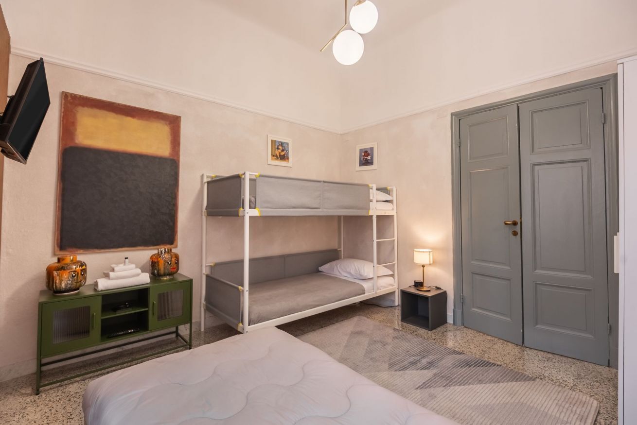 Ein Hotelzimmer mit Stockbetten, einem Schreibtisch, einem Fernseher und einem Kleiderschrank.