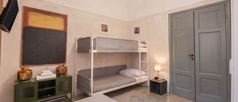 A hotel room with bunk beds, a desk, a television, and a wardrobe.