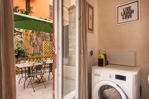 A laundry area with a washing machine, a drying rack, and a table with chairs outside. - [LaViaDelleSpezie] next station+ 5Terre + A/C (La Spezia)