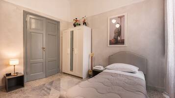 Une chambre à coucher comprenant un lit, une armoire, une table de chevet, une lampe et un tableau encadré accroché au mur.