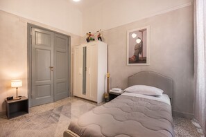Ein Schlafzimmer mit einem Bett, einem Kleiderschrank, einem Nachttisch, einer Lampe und einem gerahmten Bild an der Wand.