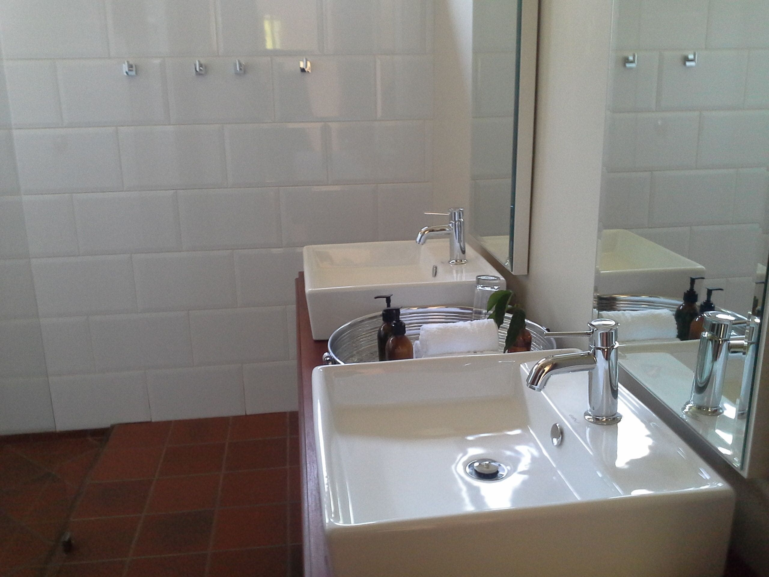 A bathroom with two sinks, a mirror, and a tiled wall.