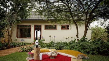 A house with a garden patio area featuring a picnic setup with food and drink.