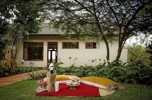 A house with a garden patio area featuring a picnic setup with food and drink.