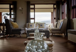 A spacious living area with a sofa set, a coffee table, and decorative glass bowls. - Acacia Farm Lodge (Karatu)