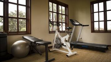 A home gym with a stationary bike, treadmill, exercise ball, and bench.