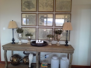 A wooden console table with decorative lamps, vases with plants, and a bull skull underfoot.