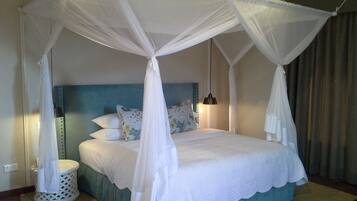 A four-poster canopy bed with a headboard, pillows, and a bedside lamp.
