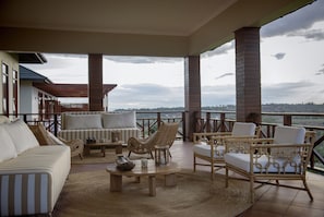 A covered outdoor seating area with a sofa, chairs, and a coffee table. - Acacia Farm Lodge (Karatu)