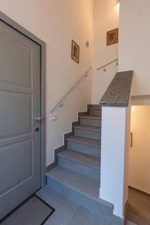 Eine Treppe mit Handlauf, einer Tür und einer Wandleuchte.