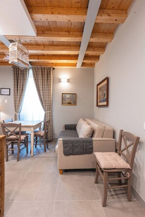 Ein gemütliches Zimmer mit Holzboden, einem Esstisch mit Stühlen, einer Couch und einem Sessel.