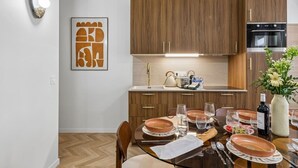 A modern kitchen with wooden cabinets, a built-in oven, and a dining area with a table set for four. - Lavie Maison - Spa Bath & AC, Heart of Saint-Merri (Paris)