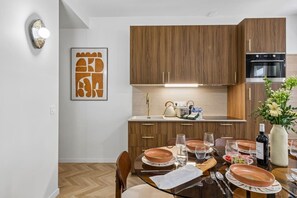 A modern kitchen with wooden cabinets, a built-in oven, and a dining area with a table set for four. - Lavie Maison - Spa Bath & AC, Heart of Saint-Merri (Paris)