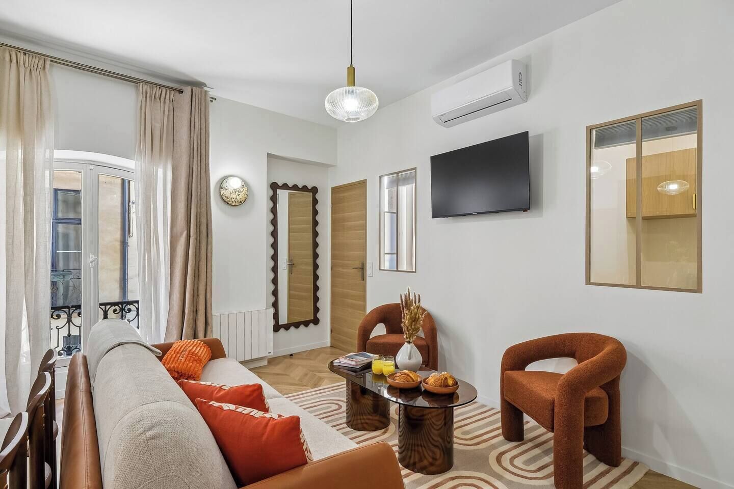 A modern living room with a sofa, armchairs, a coffee table, and a flat-screen TV.