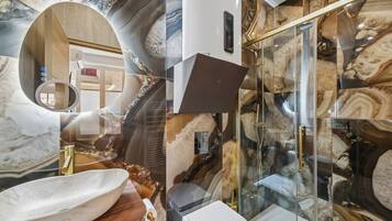 A bathroom with a large oval sink, a glass shower enclosure, and marble-like wall tiles.
